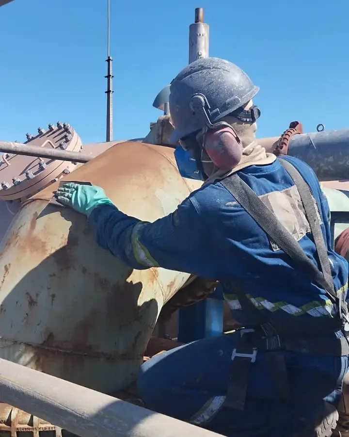 Operador com equipamento de proteção preparando a superfície de uma estrutura ao ar livre